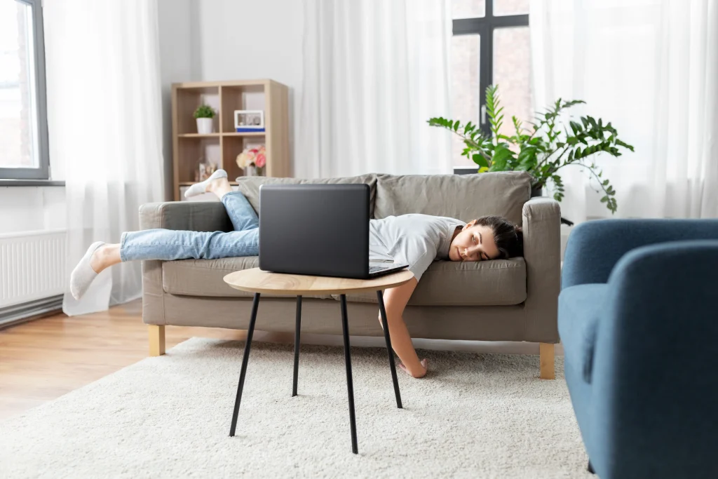 A person laying on the couch and a laptop in front of them