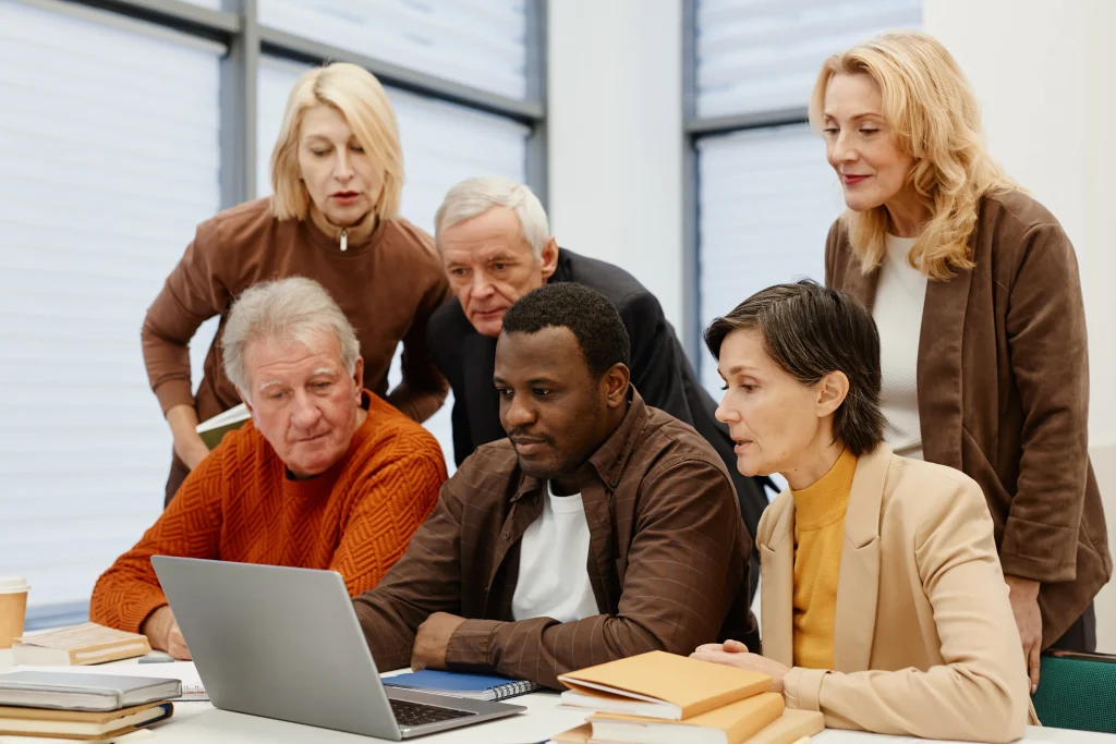 A group of older adults surrounding a laptop.