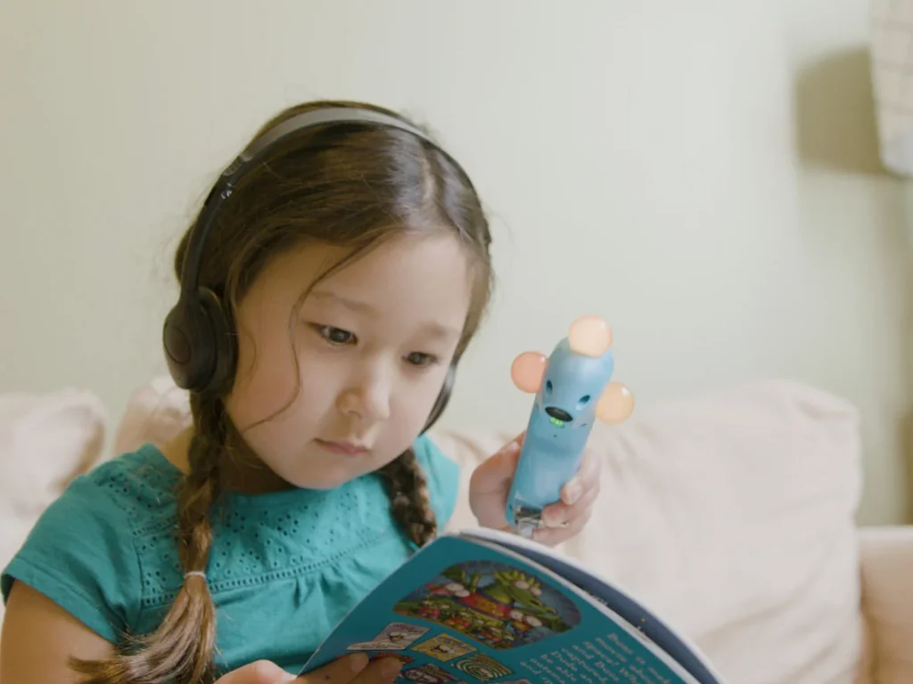 Little girl reading book with interactive wand