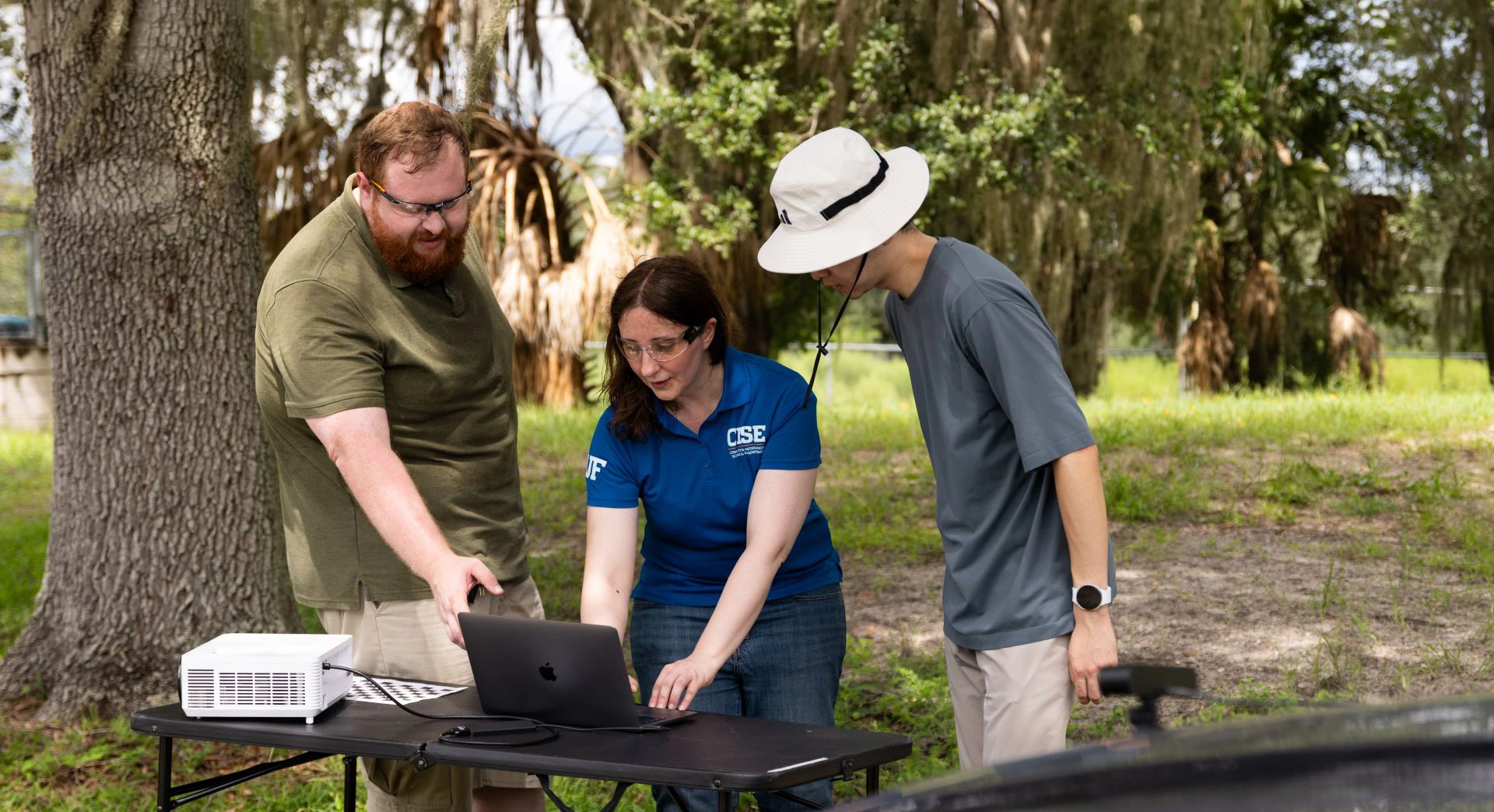 Researchers gather around a monitor in a field